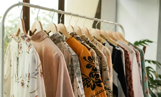 Arara de loja com blusas leves estampadas, em tons de off-white, rosa e mostarda